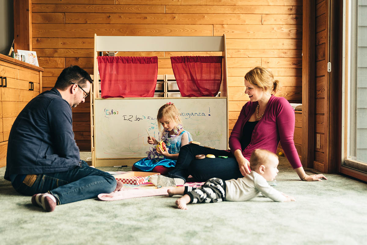 Family of four plays on the floor with little kitchen.