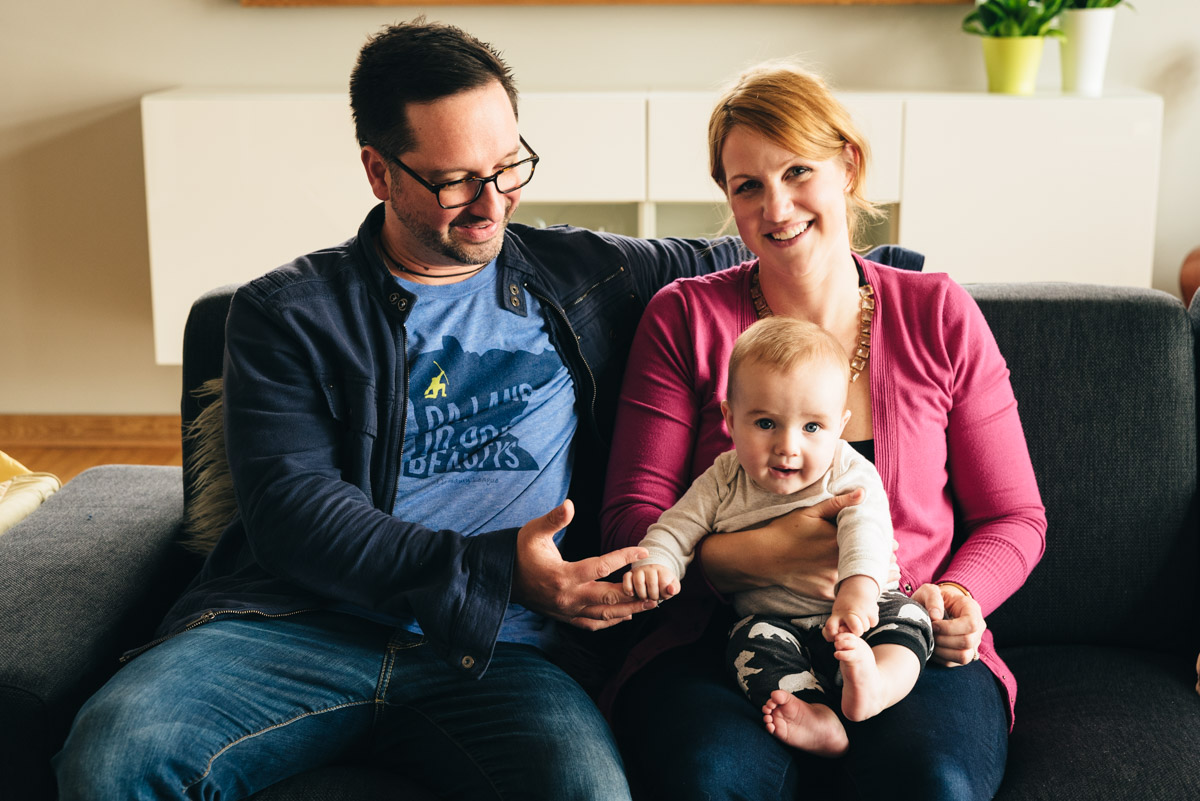 Mother, father and son sit together on a couch during a Minnesota video session.