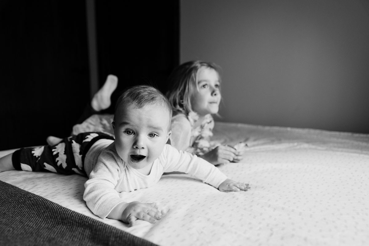 Two children laying on the bed. Image in black and white.