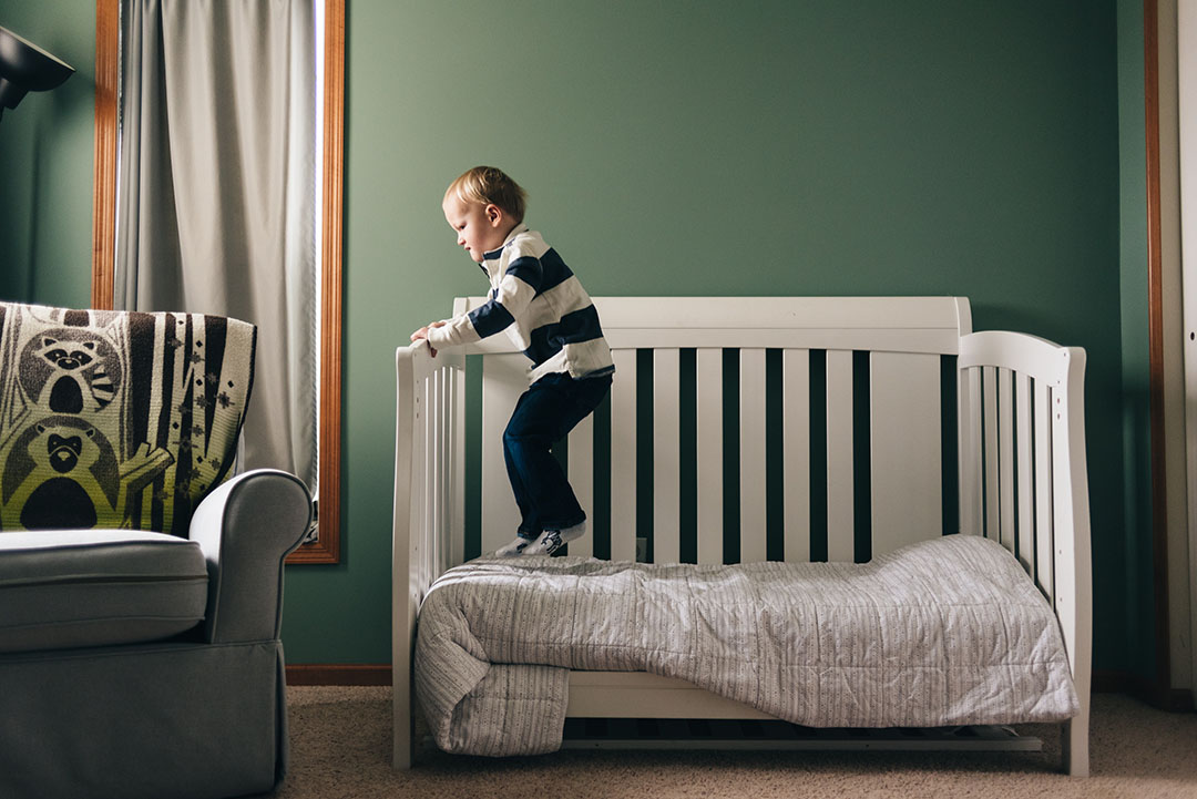 Young boy jumps on bed. Family photo session clothing options.