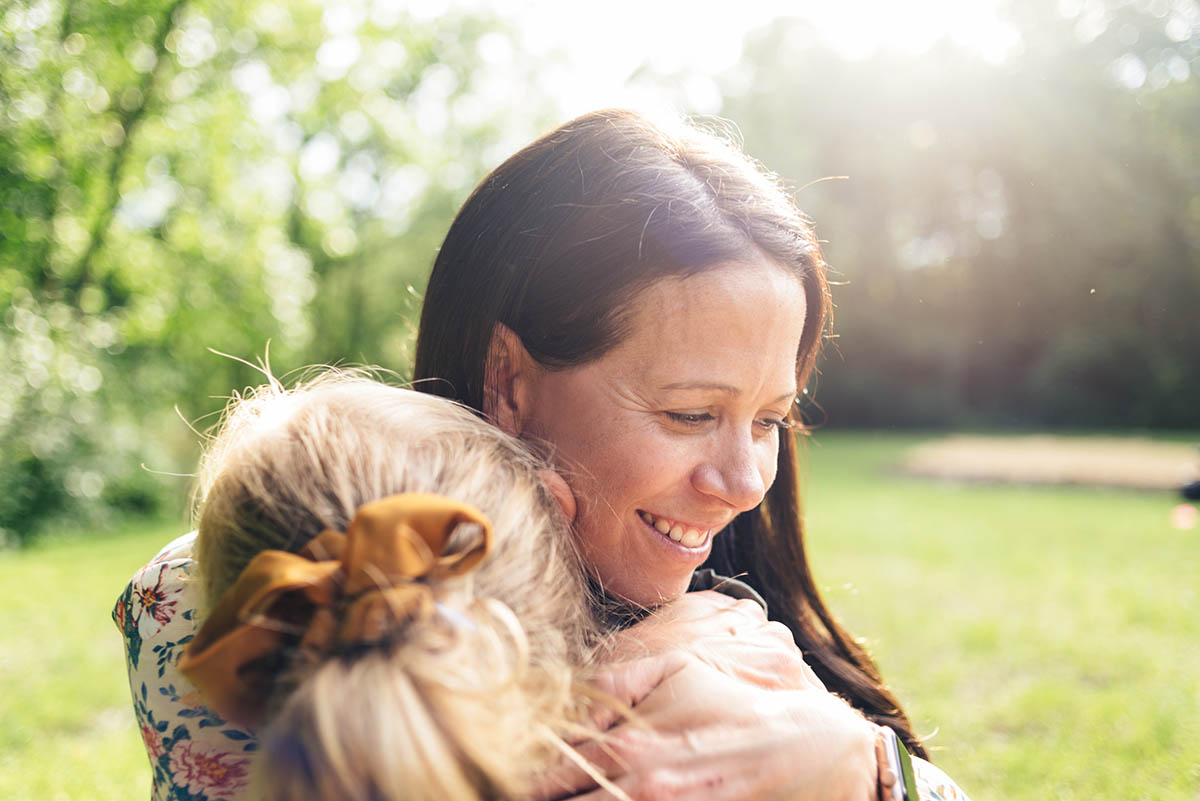 Mother hugs daughter with the sunset in the distance during family video in Minnesota.