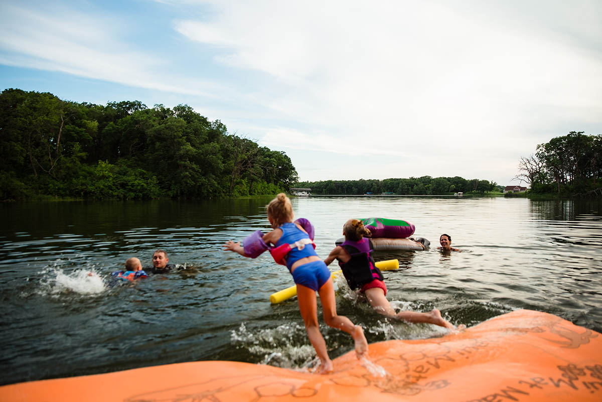 Kids jump off foam mat into the lake.