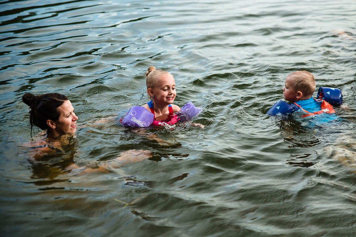 Mother and two kids swim in Minnesota lake during family video sessino.