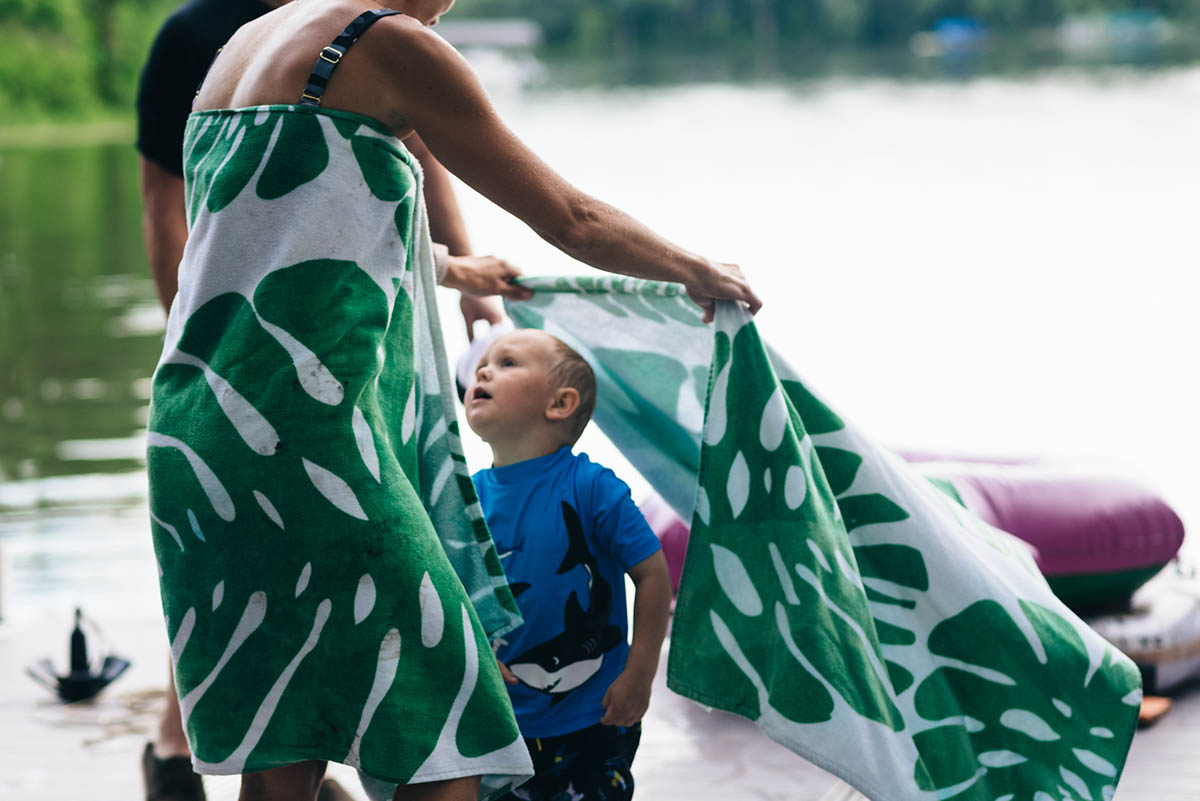 Mother wraps towel around young son after swimming in Minnesota lake.