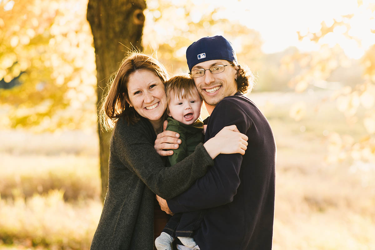 Sunset family session in Plymouth, MN. Couple hugs toddler son