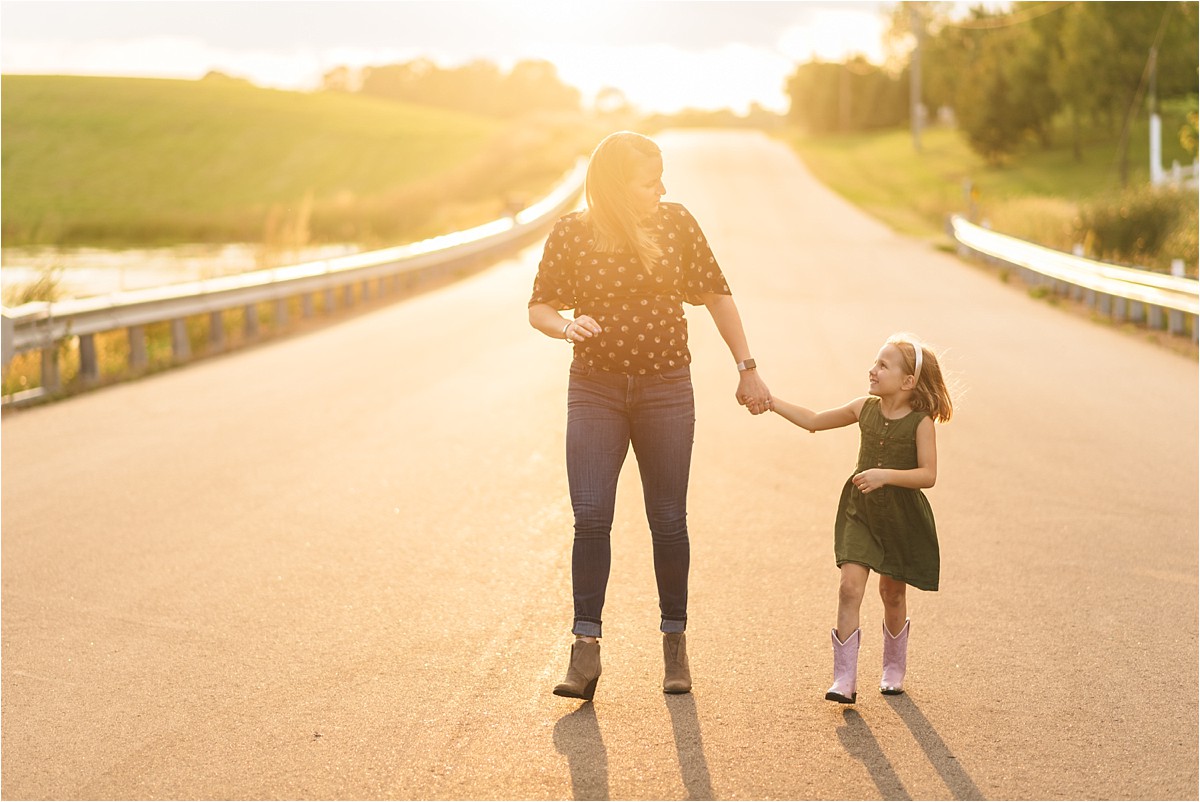 Mother and daughter walk down a road holding hands.