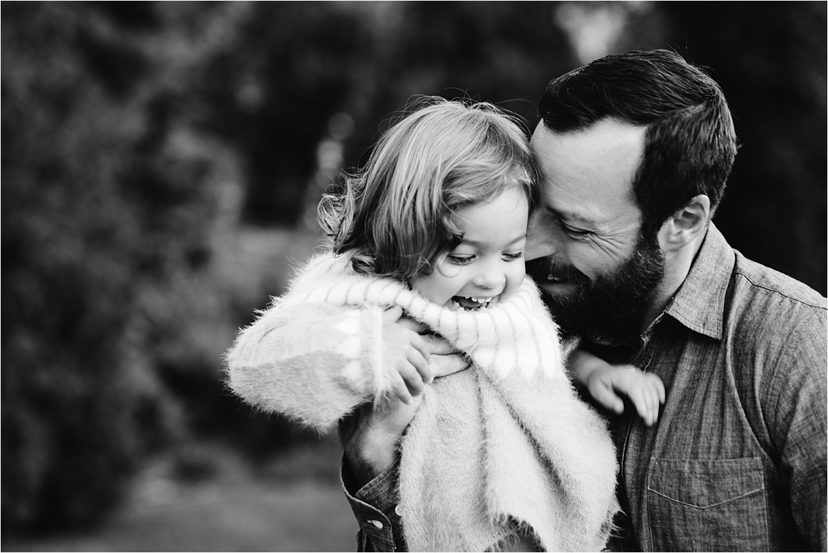 Young girl and her father snuggle during a family photos sunset session.