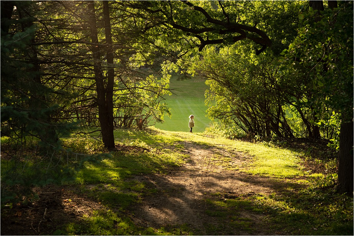 Little girl standing in far off clearing of forest in family photos sunset session.