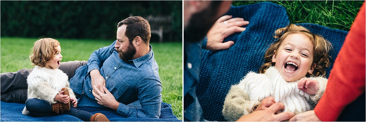 Daddy and daughter play on a blanket in the park.