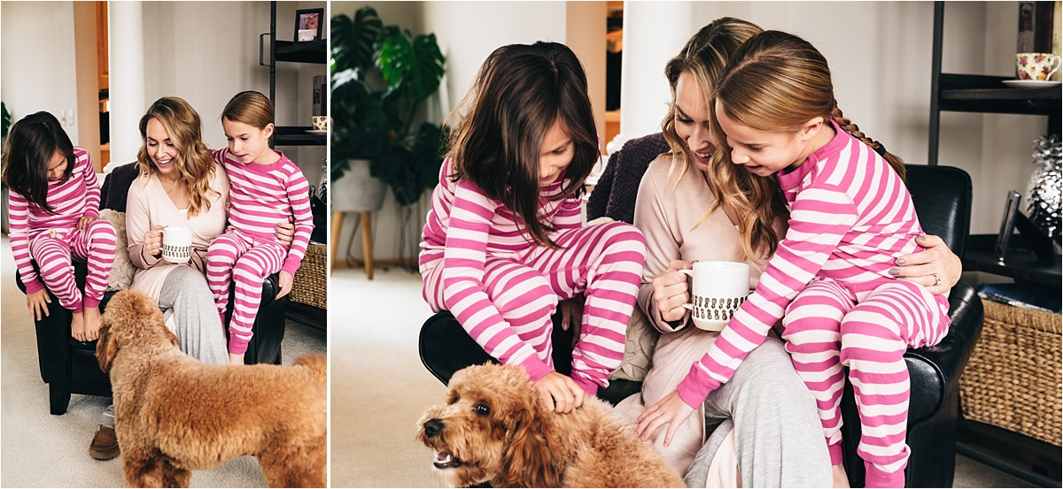 Two girls and mother sit together on a chair snuggling.