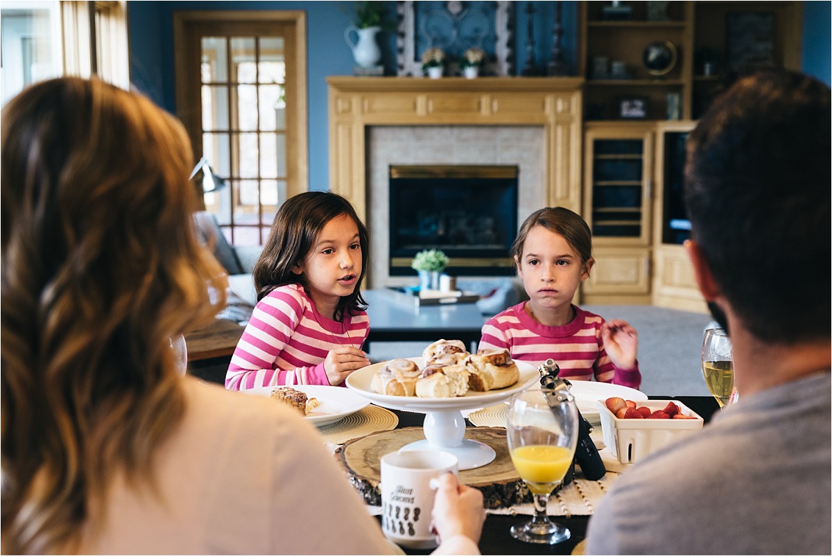 Family at breakfast, focus on two daughters eating strawberries.
