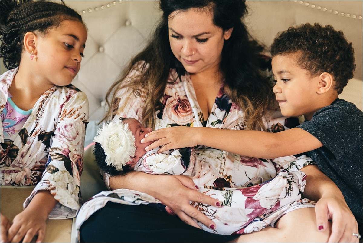 Brother and sister help care for newborn sister.