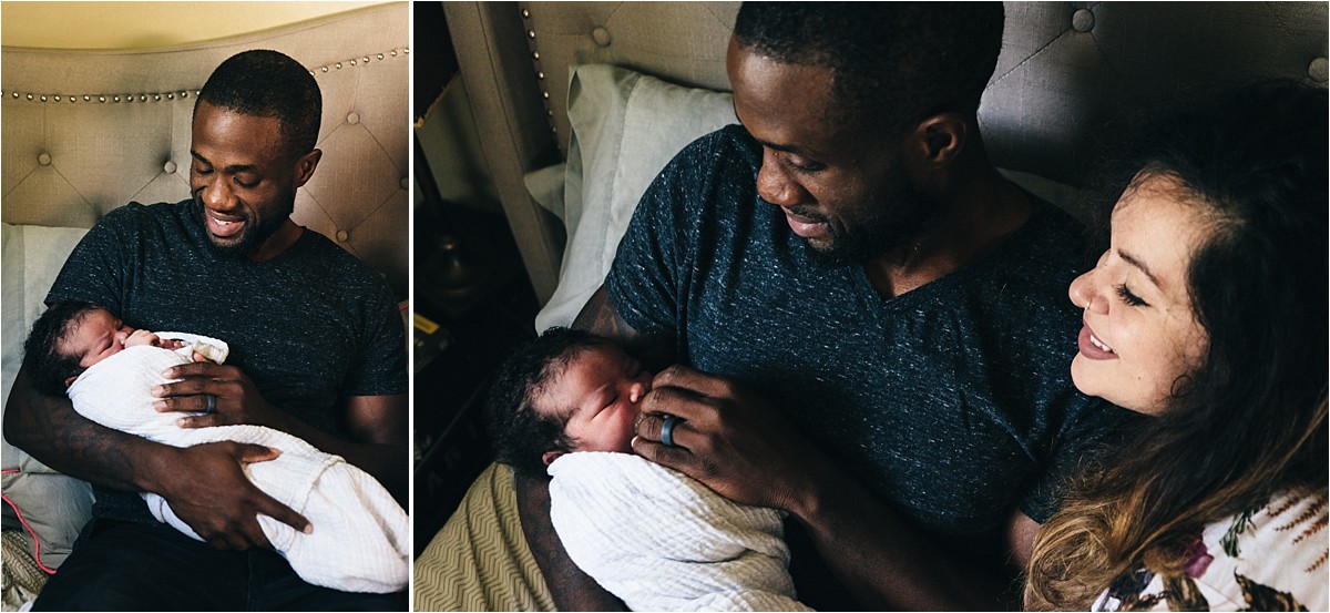 Father holds newborn baby girl and poses with mother.