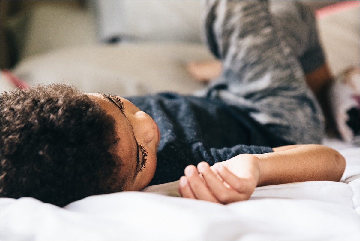 Little boy lies on bed.