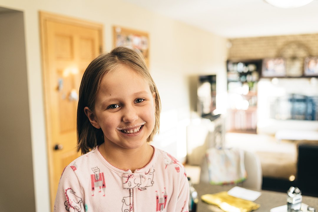 Girl with milk mustache smiles at camera.