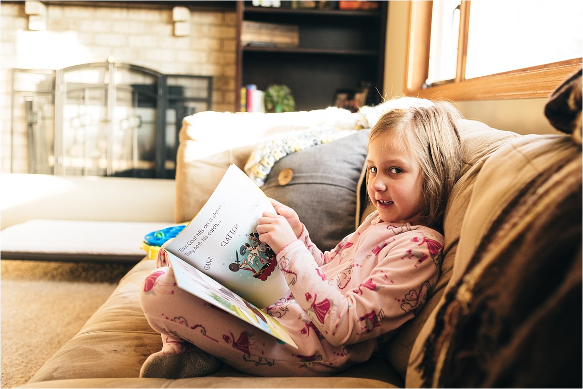 Young girl sits on couch and reads.