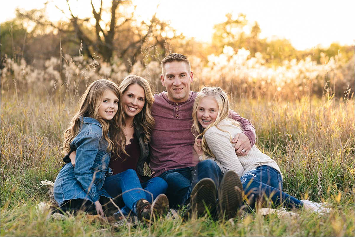 family poses at sunset in tall grass.