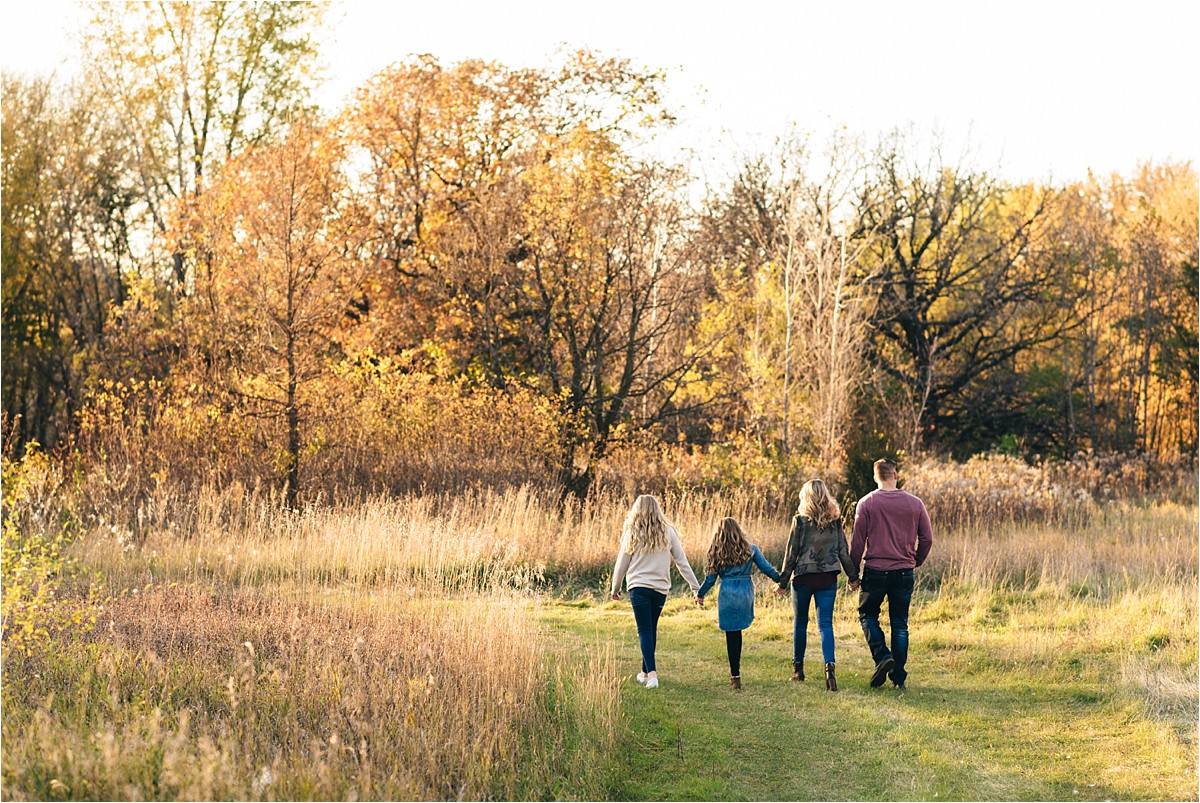 Family walks through field of tall grass away from camera.