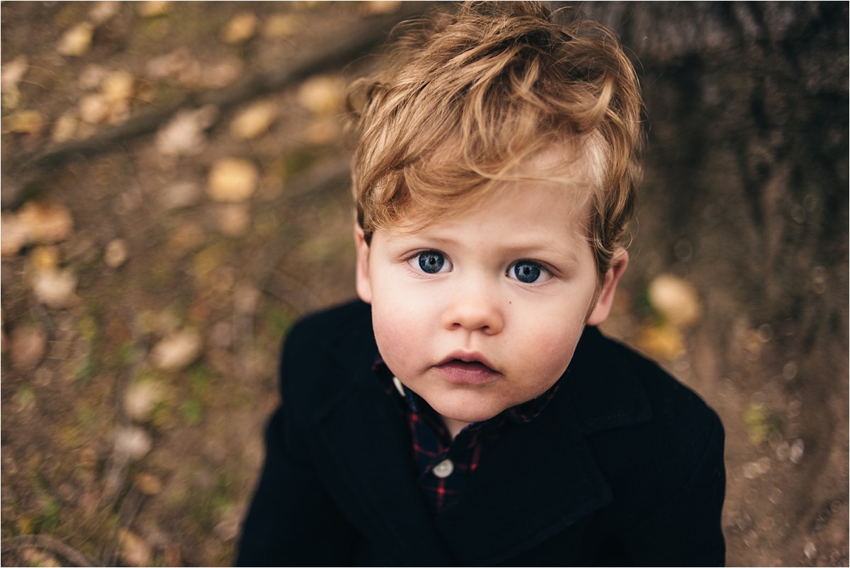 Young boy looks at camera during family sunset photography session.