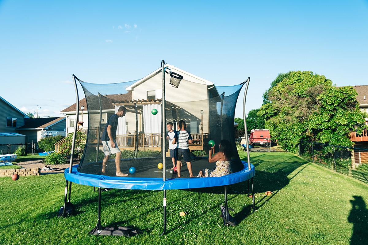 Family of four jumps on large trampoline during family photography session.