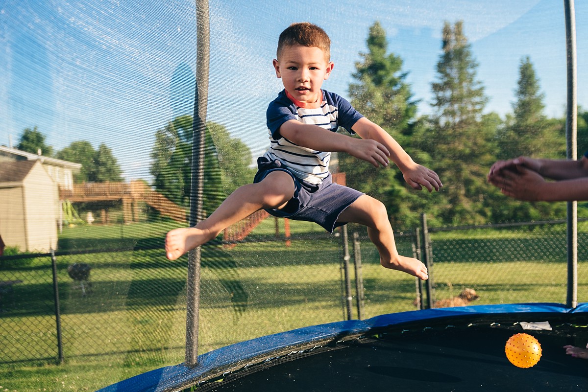 Boy jumps on trampoline and gazes at camera.