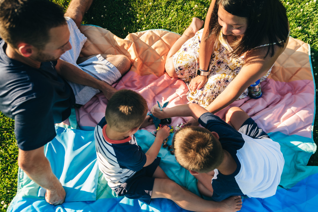 Photo from above of family playing a game on a blanket.