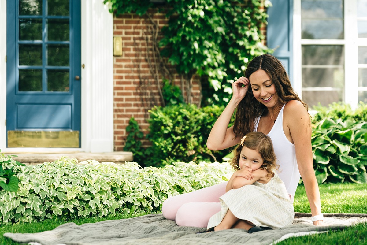 Mother and young daughter sit on a blanket talking during full family film.