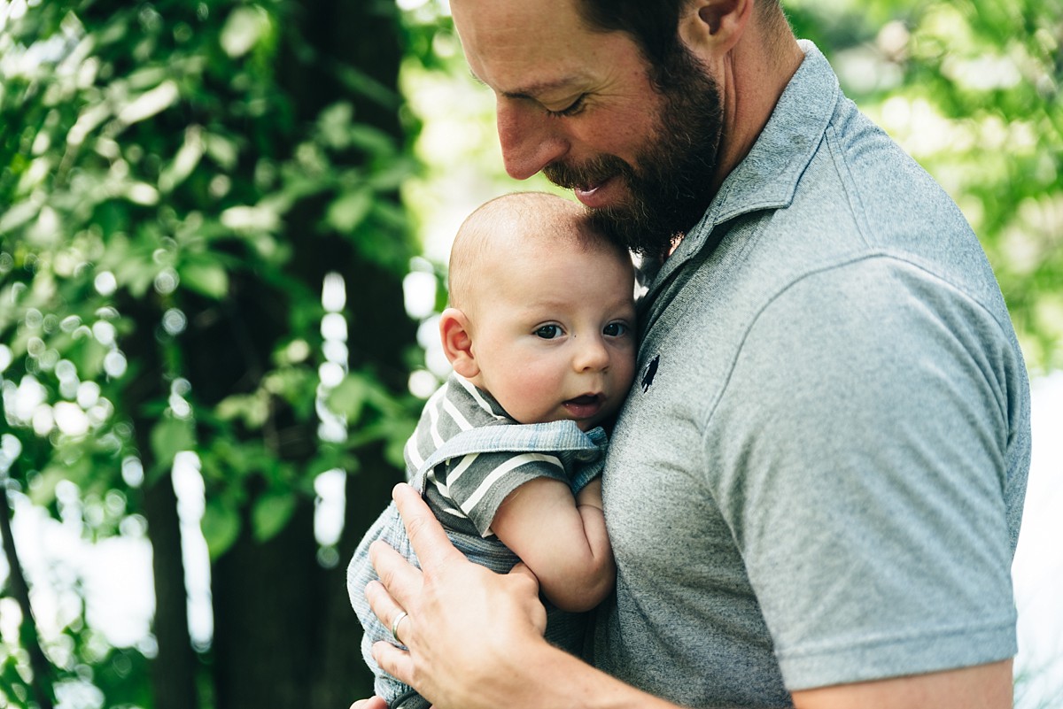 Father holds 3 month old son in his arms.