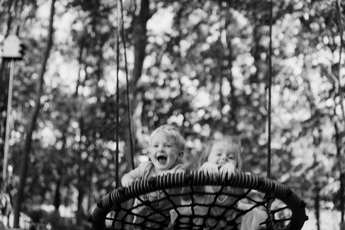 Brother and sister on swing with a look of glee.