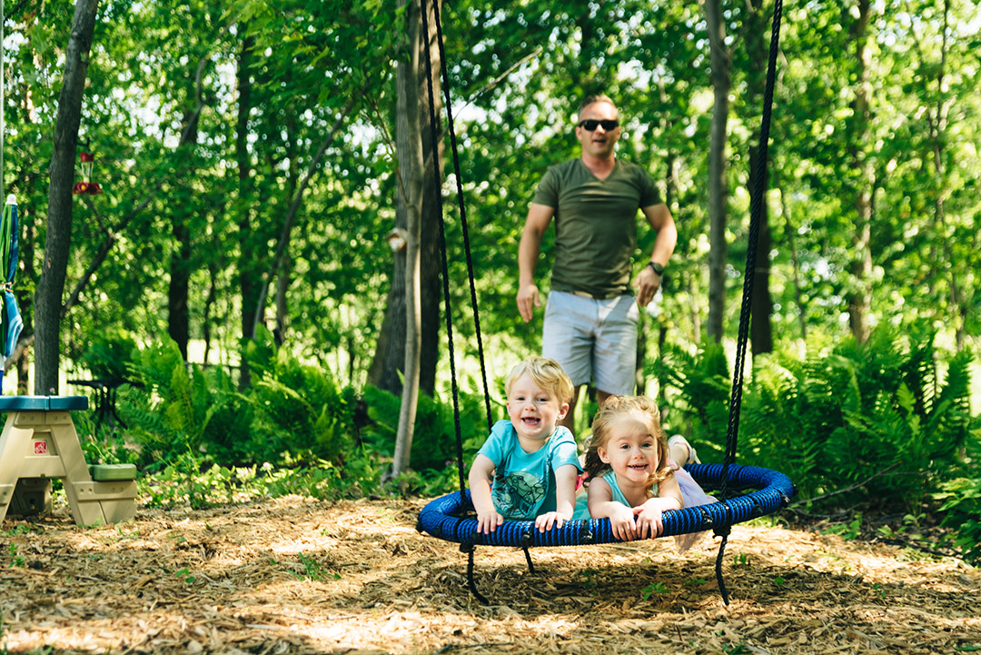 Three year olds on a swing in the backyard during Minnesota family video.