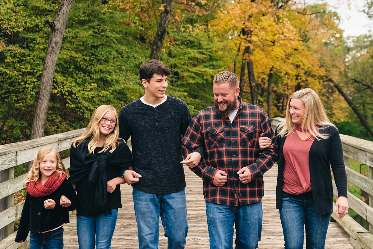 Minnesota family walks across bridge laughing during sunset photography session.