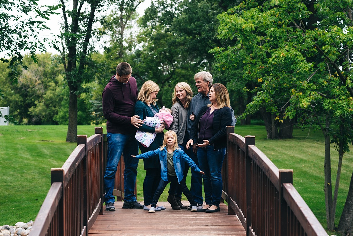 Minnesota family holds hands on bridge during a sunset photography session.