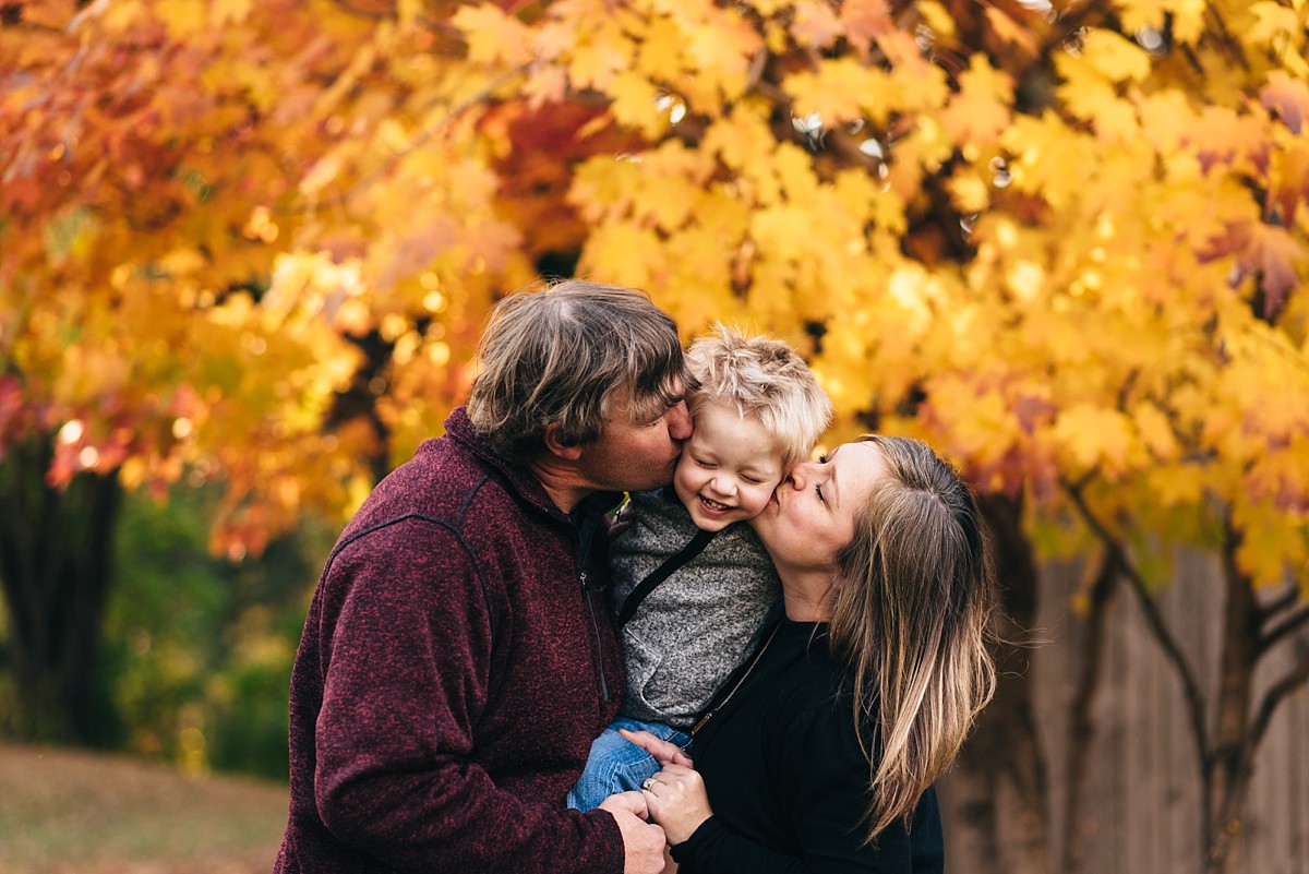 Minnesota sunset photography sessions mother and father kiss son.