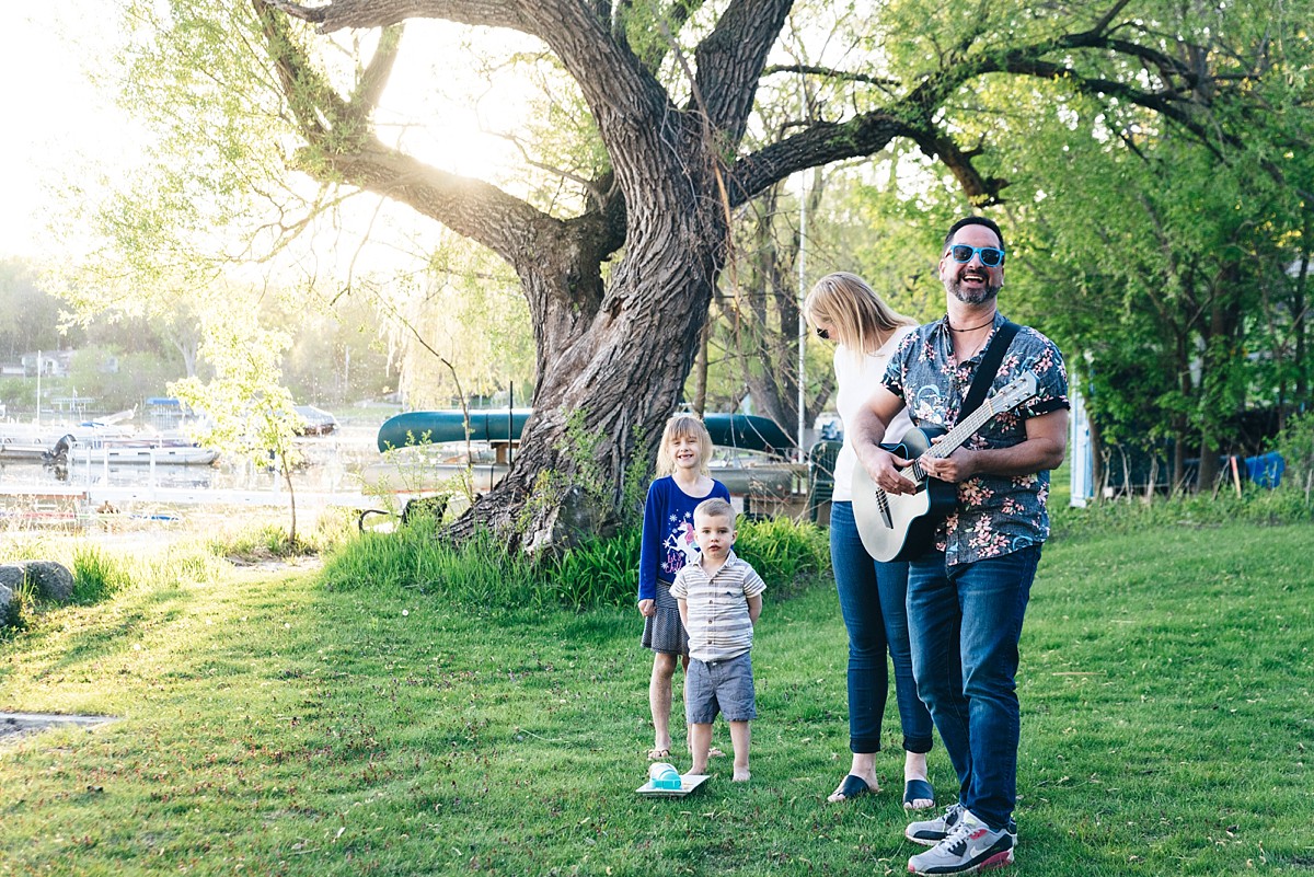 Minnesota father plays guitar to his family near a lake.