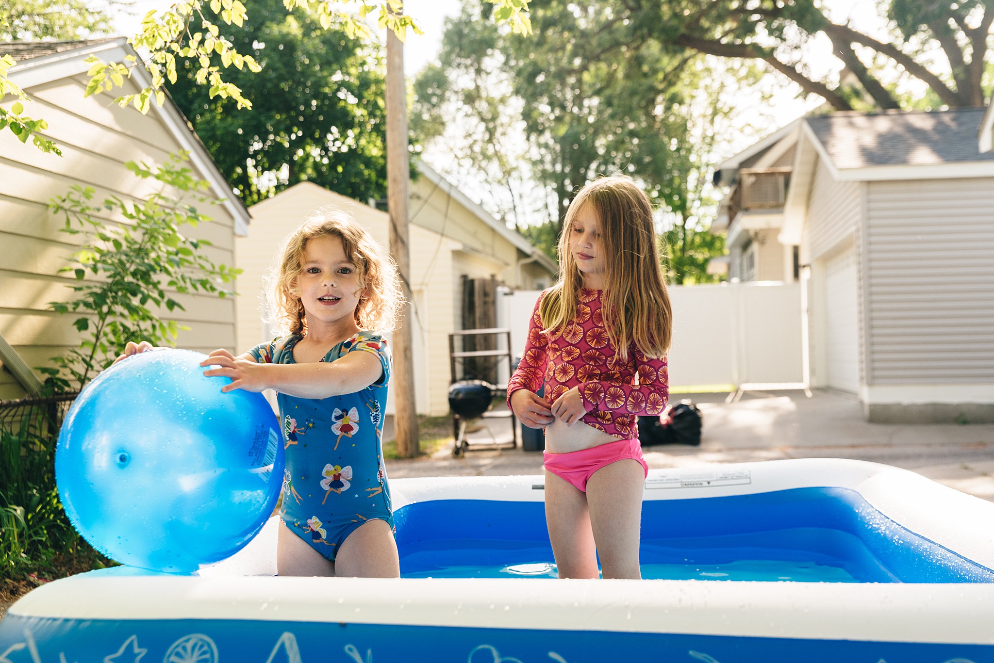 Two girls play in kiddie pool during Edina family video session.