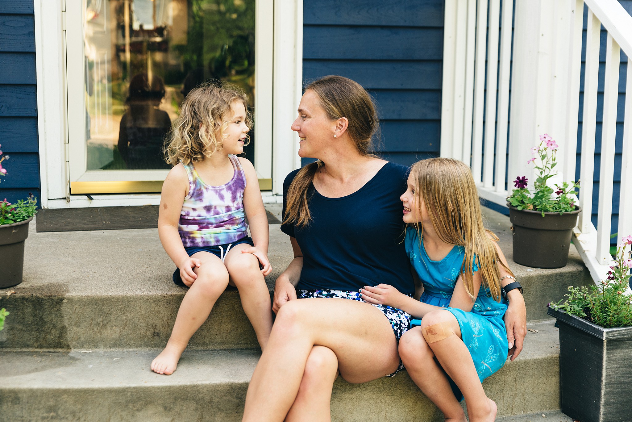 Mother and two daughters sit on a porch during Edina family video