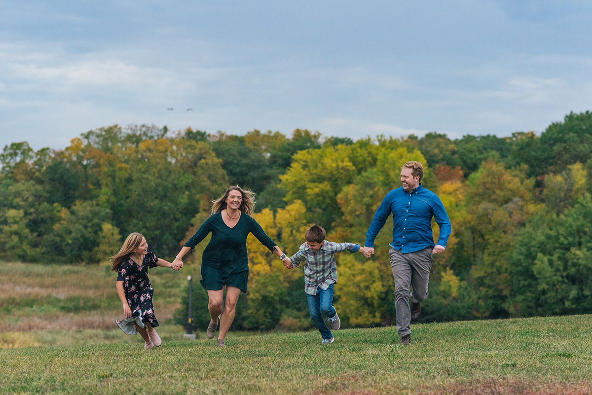 Family runs toward camera holding hands and laughing.