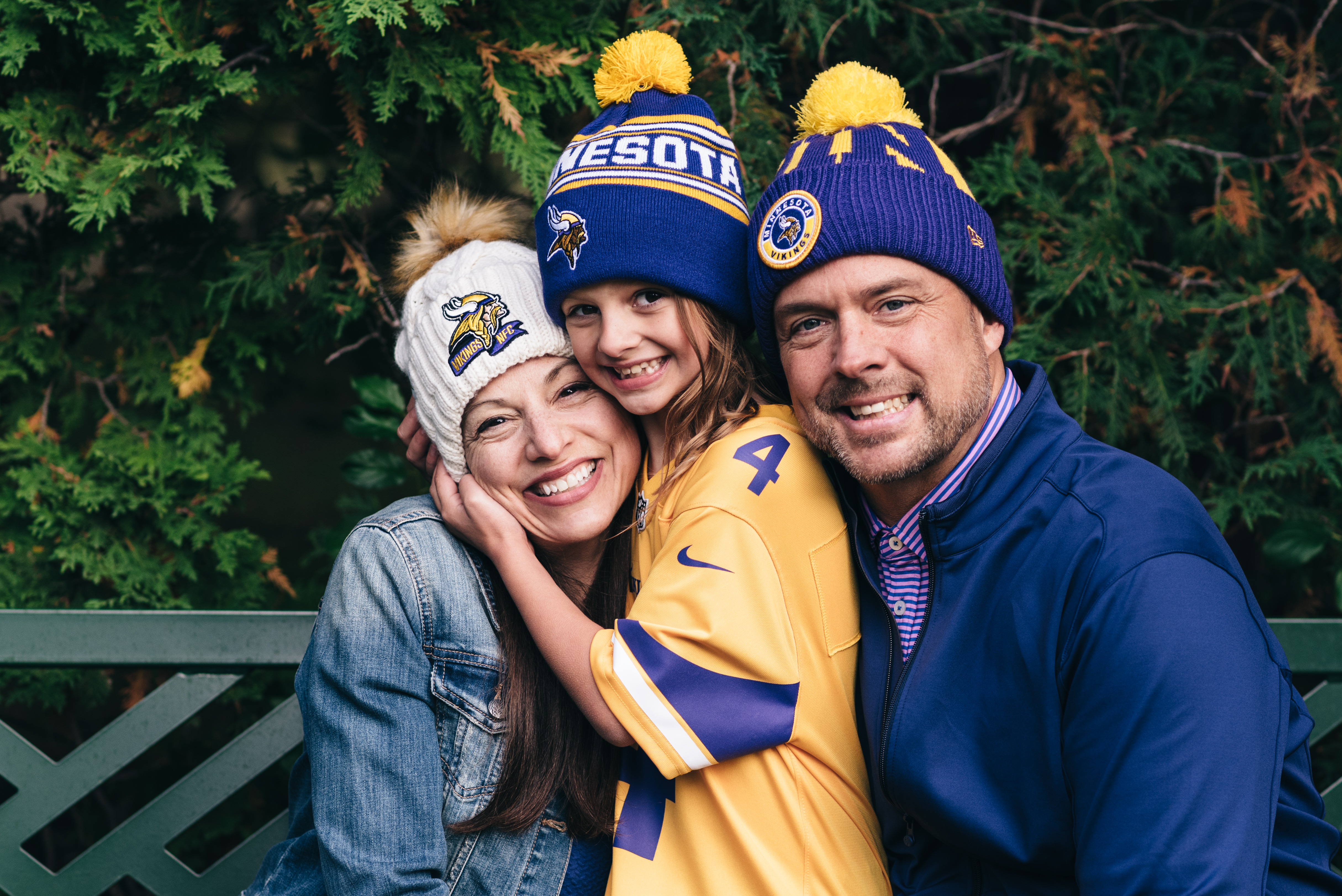 Family of three wear MN Vikings hats and pose for photos.