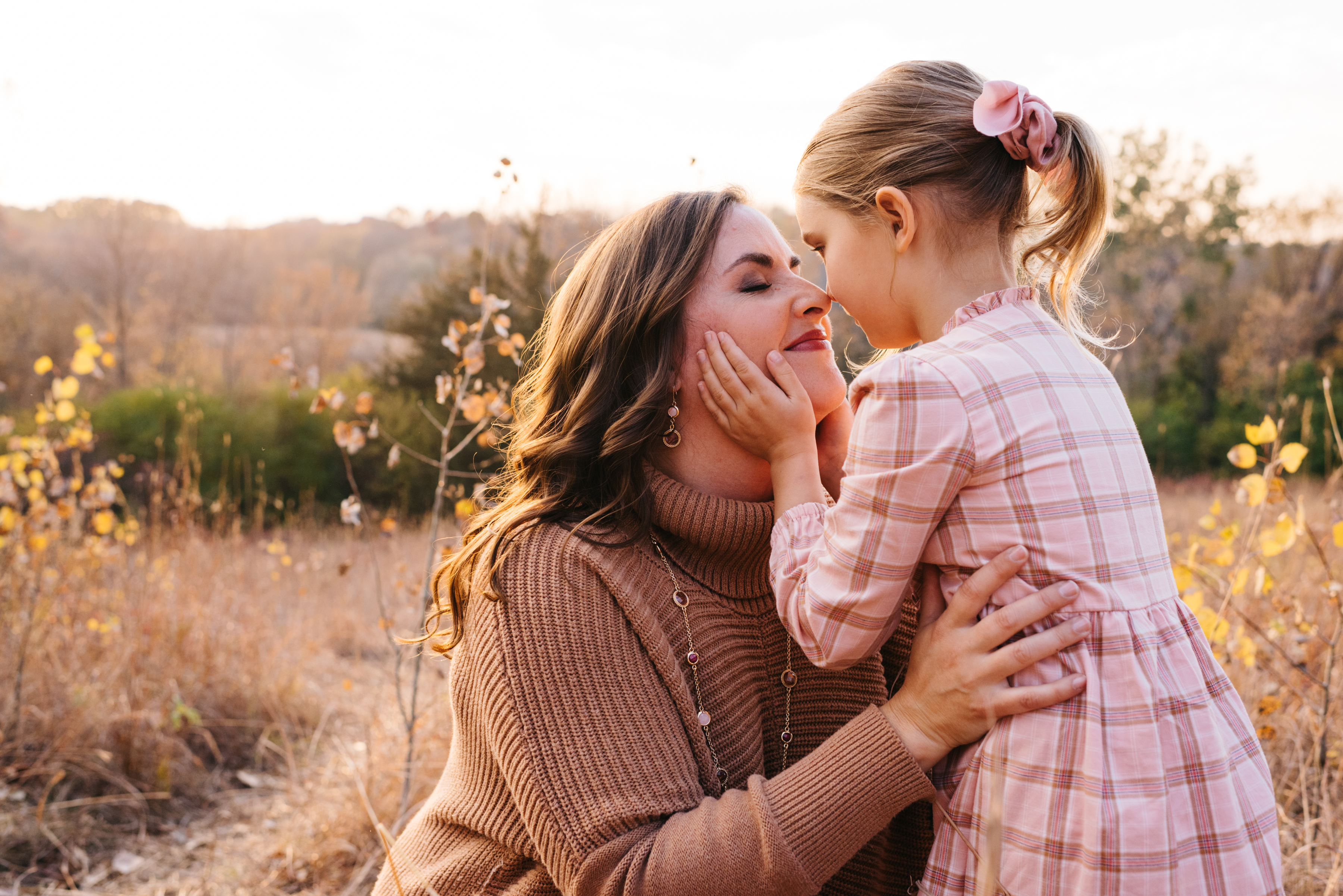 Mother and daughter rub noses together during sunset session.