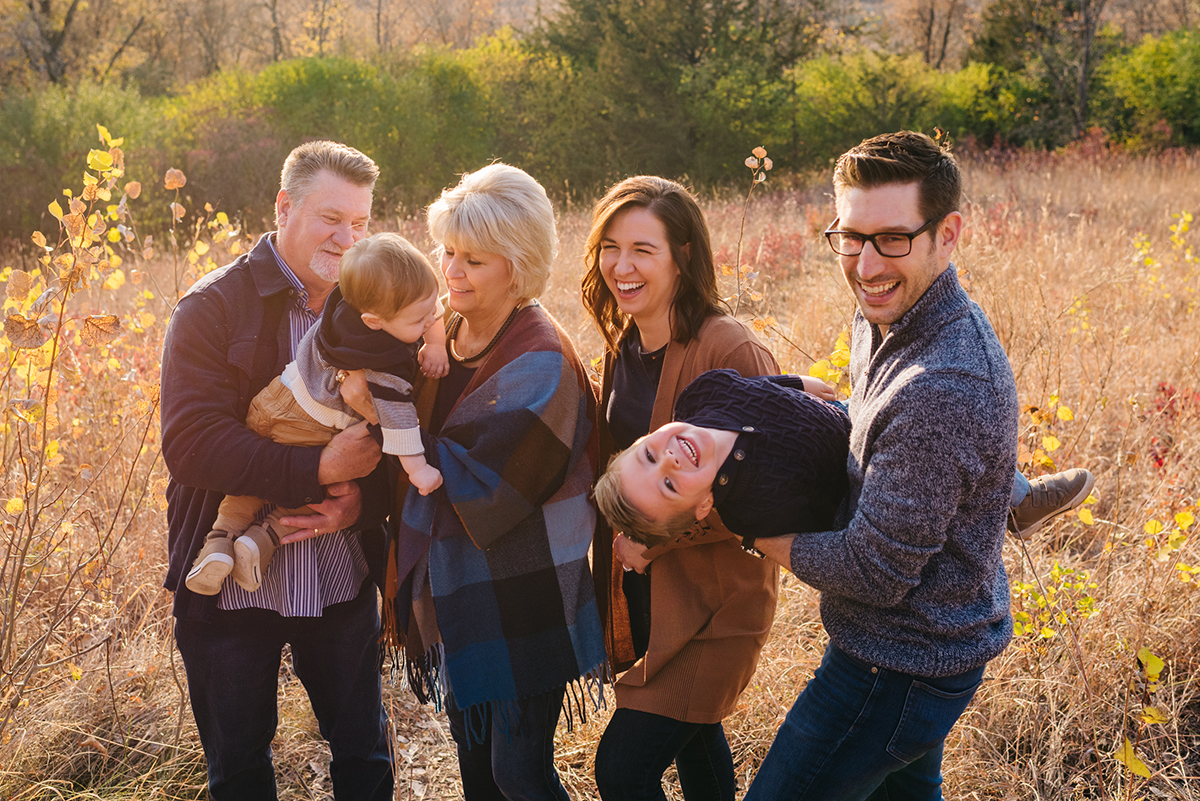 Grandparents, parents and two kids laugh and snuggle in sunset sessions photos.