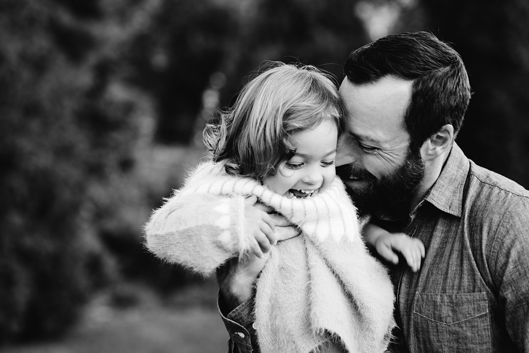 Father hugs his daughter while she laughs. Black and white image.