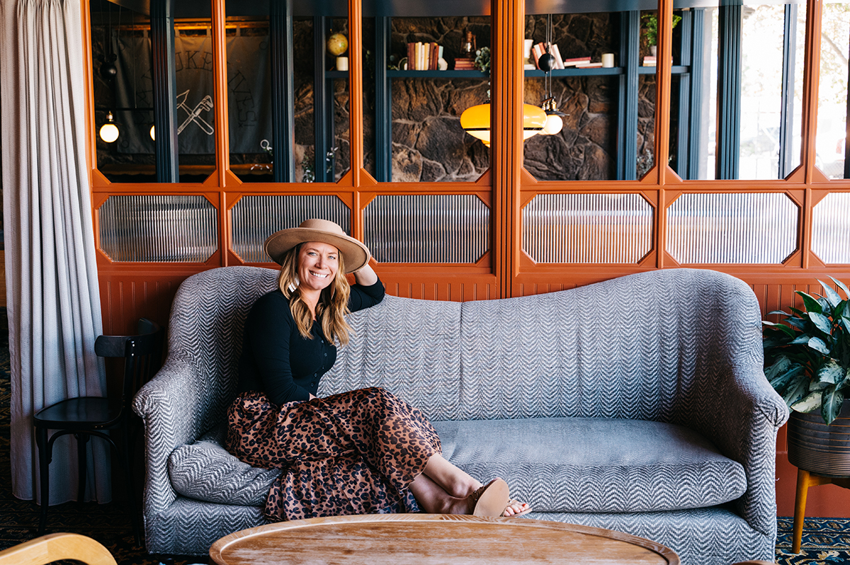 Woman sits on a couch with hat smiling at camera during Flagstaff branding sessions at High Country Motor Lodge. 