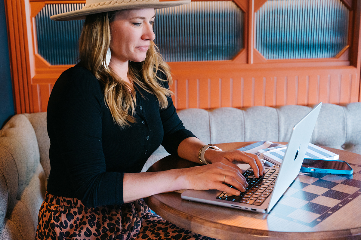 Woman sits at table working on her computer