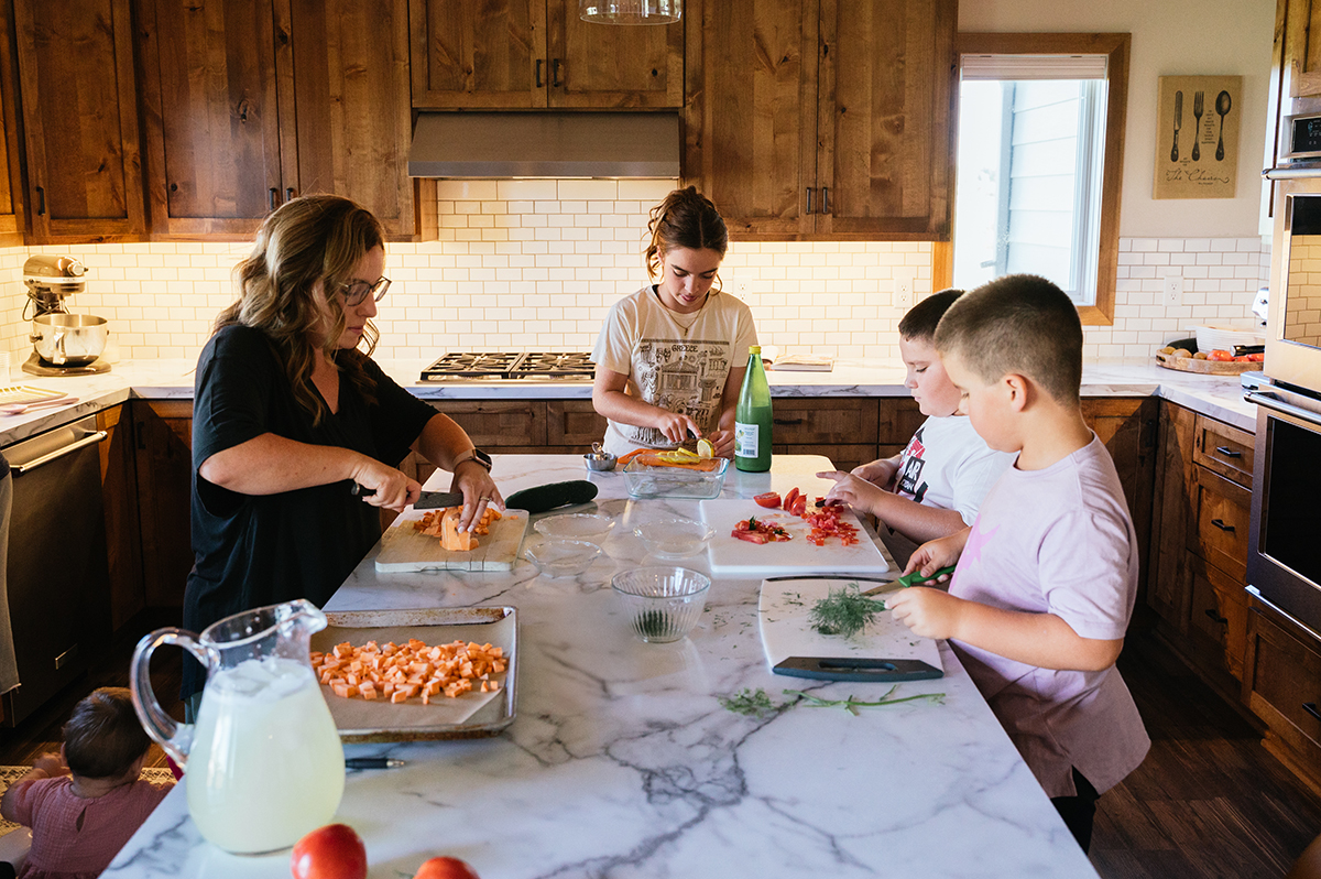 Mom, daughter and two sons cook in the kitchen during Northwest Minnesota family film.
