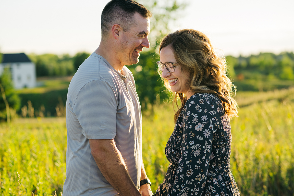 Couple holds hands and faces each other laughing