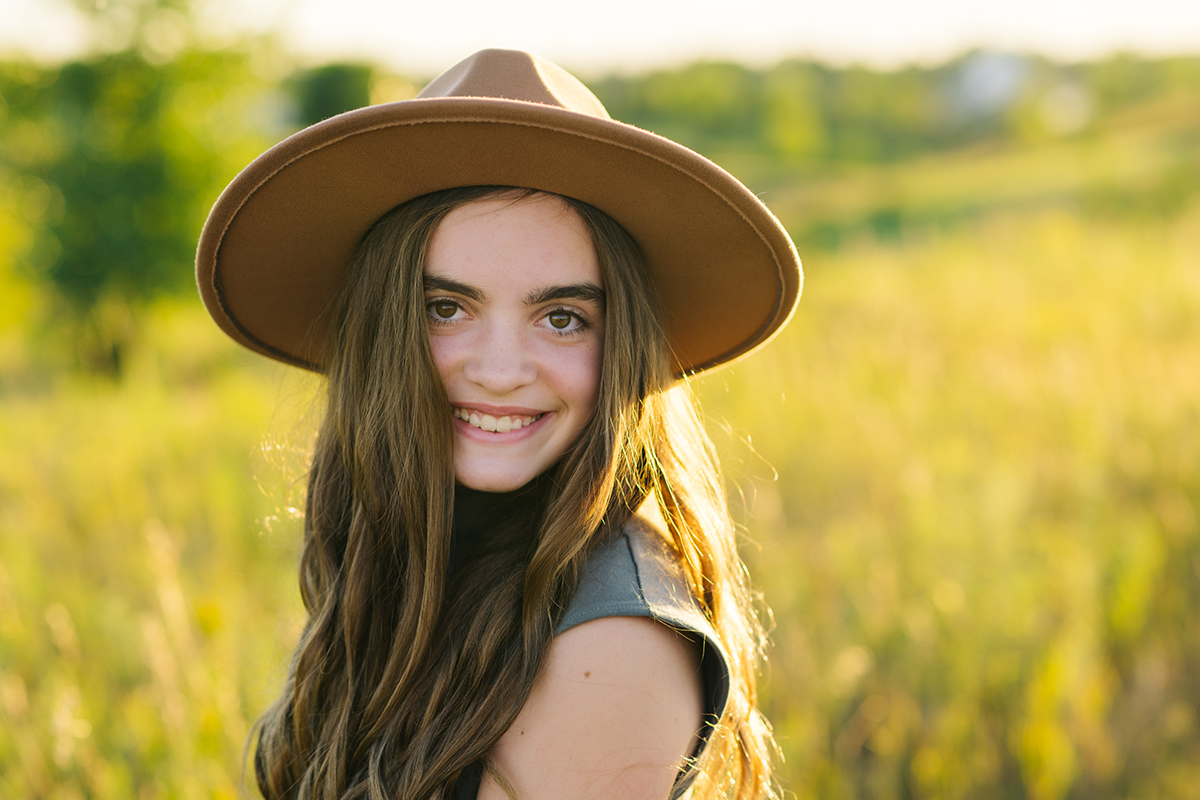 Teenage girl in hat smiles at camera during Northwest Minnesota family film.