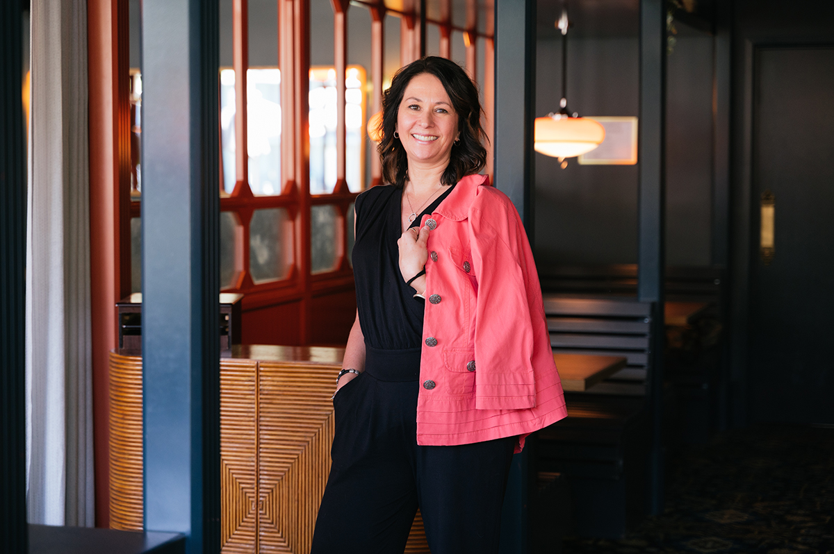 Rebecca Coresado poses at High Country Motor Lodge near orange windows.