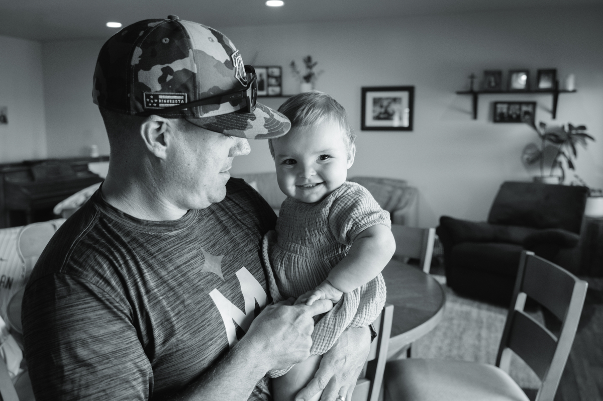 Dad holds toddler daughter as she laughs at him.