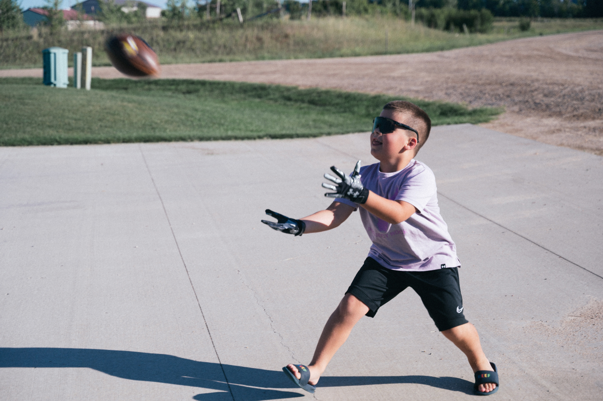 Boy catches football in driveway.