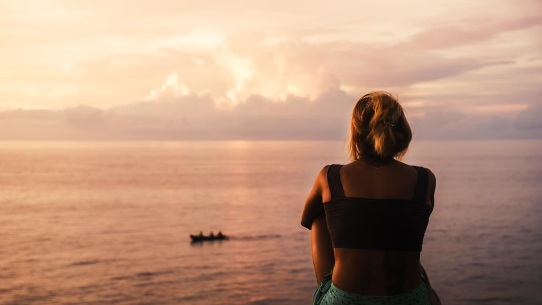 woman sits on the cliff of sumba sunset cliff looking out over the golden horizon woman sits on the cliff of sumba sunset cliff looking out over the golden horizon